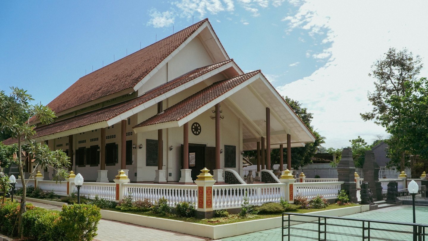 A multi-tiered temple features red tiled roofs and white walls.