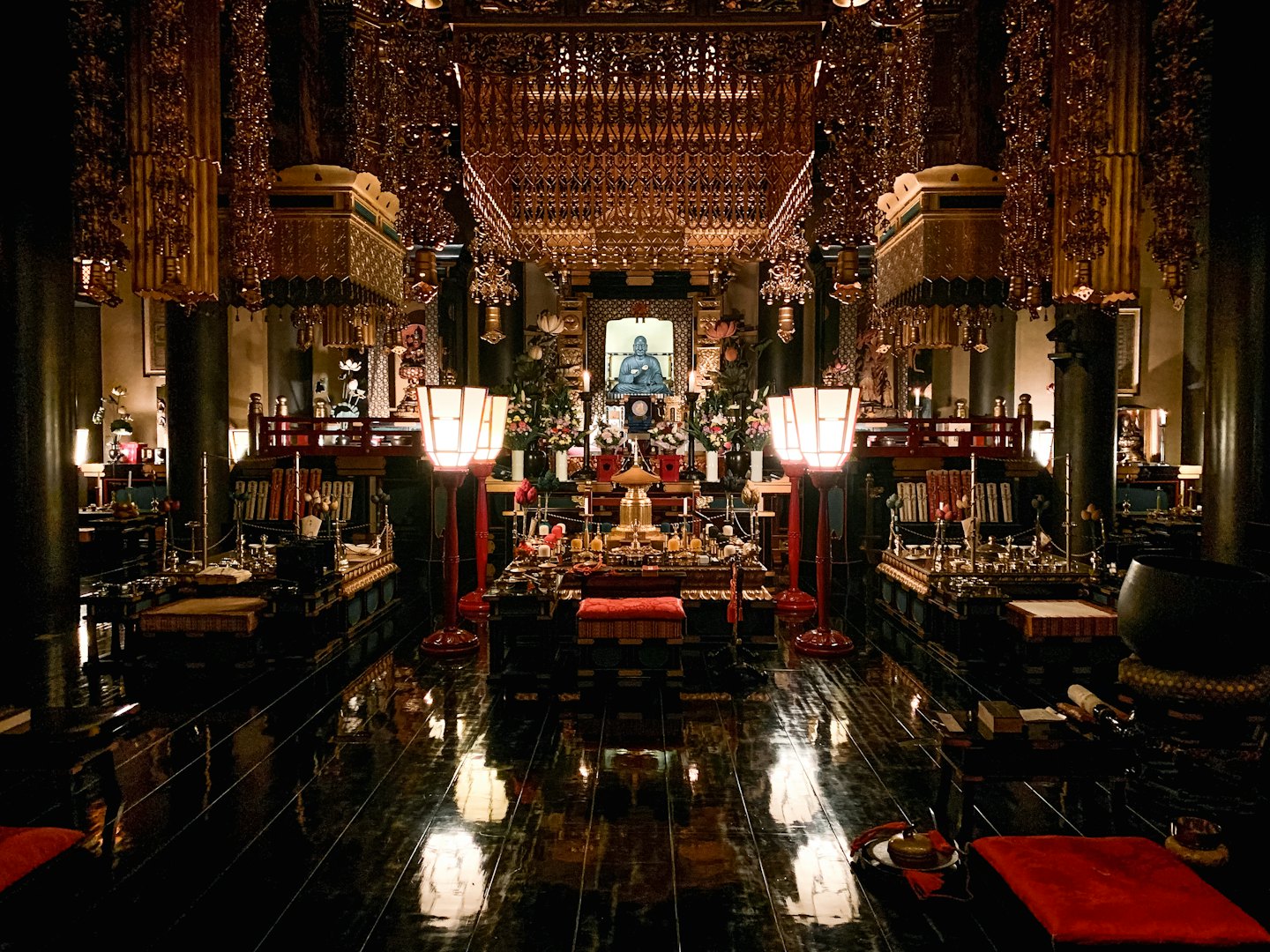 Golden Buddha statue on ornate altar in dimly lit temple.